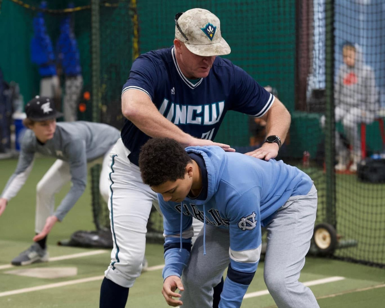 Trent mongero adjusting a campers fielding positioning at a dirt bros elite infield camp