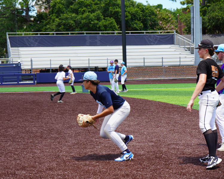 Teenage camper attacking a ground ball while taking infield practice at a dirt bros baseball camp